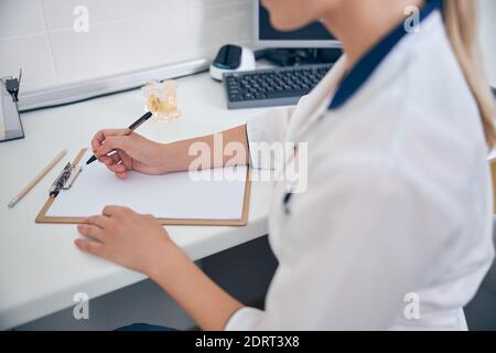 Frau in medizinischen Uniform Schreiben am Schreibtisch Stockfoto