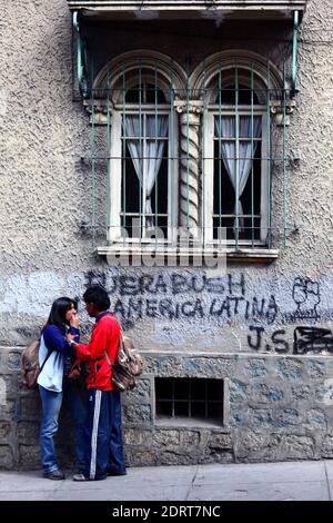 Junges Paar steht neben der Wand mit Bush aus Lateinamerika / Fuera Bush de America Latina Graffiti, La Paz , Bolivien Stockfoto