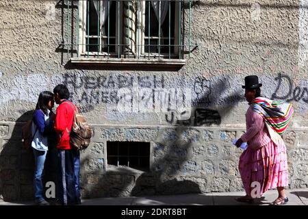 Aymara Frau im traditionellen Kleid an Bush vorbei aus Lateinamerika / Fuera Bush de America Latina Graffiti an der Wand, La Paz , Bolivien Stockfoto