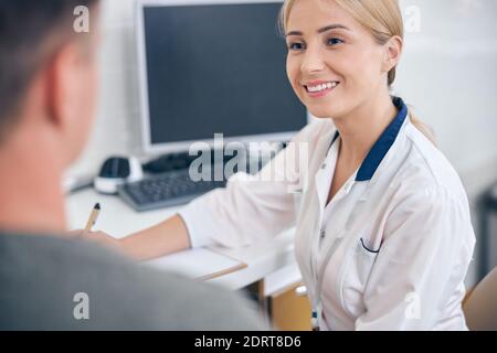 Lächelnde Zahnärztin schreibt sich der Mann beschwert Stockfoto