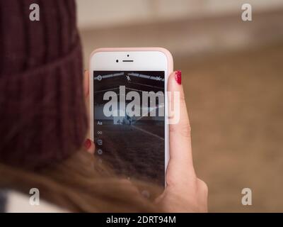 Rückansicht der Frau mit roten Nägeln machen Video mit Telefon bei Dressur Contest. Stockfoto