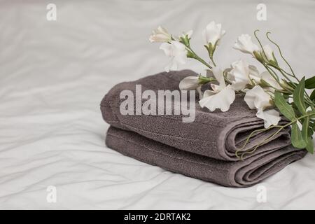 Graue Frotteetücher sind auf dem Dach mit weißem pastellfarbenem Leinen, einer weißen Blume gestapelt. 25. Mai Tag Handtücher. Speicherplatz kopieren Stockfoto