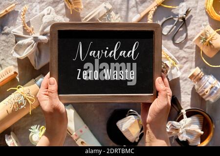 Hand halten Tafel, Kreidetafel mit Text Navidad Zero Waste auf Spanisch. Das ist Zero Waste Christmas auf Englisch. Umweltfreundliche Geschenke auf warmen Leinen t Stockfoto