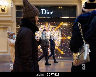 Die Menschen gehen an der hellen Vitrine von Dior vorbei.im Dezember feierte das wichtigste Kaufhaus des Landes, GUM, seinen 127. Geburtstag. Dies ist ein muss für Moskauer Einwohner und Besucher. Traditionell verwandelt SICH DAS GUMMI zum Neujahr in ein fabelhaftes Land, und vor seiner Fassade, direkt am Roten Platz, ist eine Eisbahn den ganzen Winter geöffnet. Stockfoto