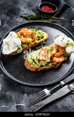 Sandwich garniert mit frischen Garnelen, Garnelen auf Avocado mit Ei. Ein gesundes Essen, skandinavische Küche. Schwarzer Hintergrund. Draufsicht. Stockfoto