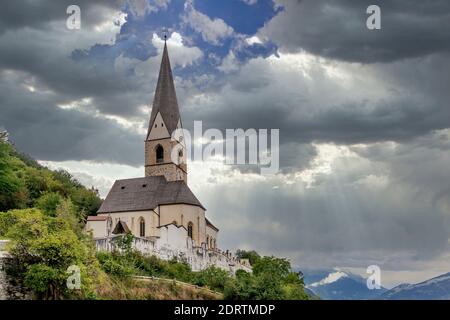 Die Kirche von San Giorgio in Agumes unter einem dramatischen Himmel, Südtirol, Italien Stockfoto