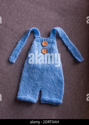 Gestrickter Jumpsuit für ein Neugeborenes auf grauem Hintergrund Stockfoto