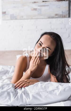 Lächelnd junge Brünette Frau im Bett Stockfoto