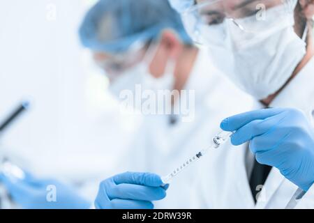 Nahaufnahme. Spritze mit einem neuen Impfstoff in den Händen eines Sanitäter. Stockfoto