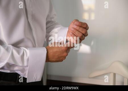 Bräutigam schließt Manschettenknöpfe an der Manschette seines weißen Hemdes. Stockfoto