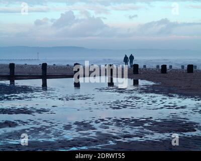 Winterblick auf den Strand in Bridlington ein beliebter Badeort im Osten Reiten von Yorkshire England Großbritannien mit paar zu Fuß in der Nähe. Stockfoto