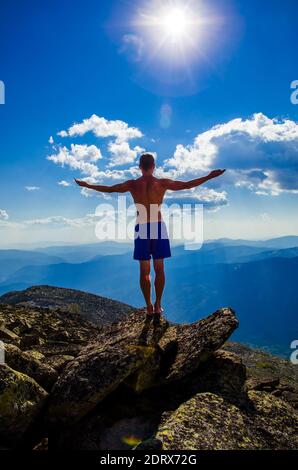 Der Mensch steht auf einem Berg mit offenen Händen. Oben auf dem Berg ist ein Mann mit weit ausgebreiteten Armen. Stockfoto