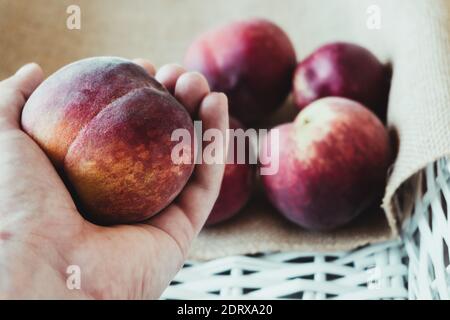 Nahaufnahme pflücken einen Pfirsich aus einer weißen Holzkiste Stockfoto