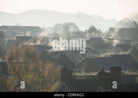 Dampf aus Heizungsanlagen und Dächern, die nach einer kalten Nacht von der Morgensonne erwärmt werden. England GB Stockfoto