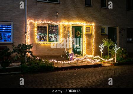 Nachtansicht von vielen Lichtern auf der Vorderseite eines Hauses in einer holländischen Stadt. Weihnachtsdekoration. Stockfoto