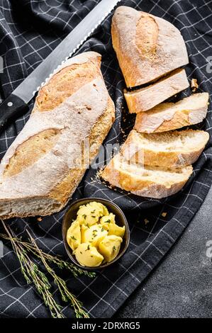 Handwerkliche Baguettes und Schnittscheibe mit Butter. Schwarzer Hintergrund. Draufsicht. Stockfoto