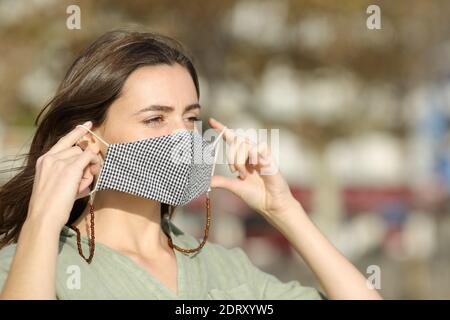 Frau geht Putting Maske durch covid in der Straße Stockfoto