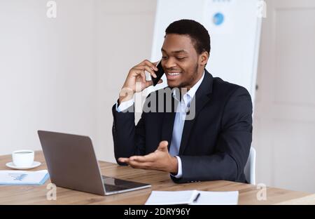 Positiver schwarzer Manager, der mit Geschäftspartnern telefoniert Stockfoto