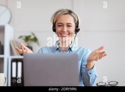 Junge Frau in Kopfhörer Teilnahme an Bildungs-oder Business-Online Konferenz auf Laptop von zu Hause aus Stockfoto