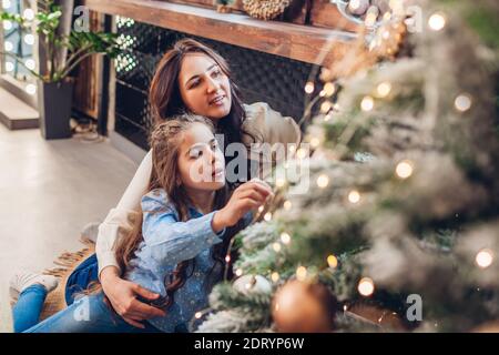 Mutter und Tochter bewundern Weihnachtsbaum zu Hause. Frohe Weihnachten und Frohes neues Jahr. Familie mit Spaß genießen Winterurlaub Feier Stockfoto