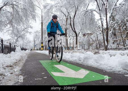 Ein Mann fährt im Winter auf dem Radweg mit dem Fahrrad. Umweltfreundliches Verkehrsmittel in der Stadt Stockfoto