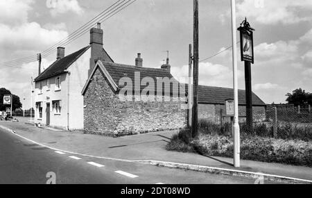 Half Moon in Mudford, in der Nähe von Yeovil in oder kurz vor 1975. Eine vordere und seitliche Höhe. Spätere Fotos zeigen ein zusätzliches Vordach über der Haupttür. Die Bushaltestelle wirbt mit Zeiten für Wake's Services, das Pub-Postschild zeigt eine Eule vor einem Halbmond und die BP-Garage bietet 24 Stunden Benzin (Tankstelle ist jetzt weg und ist 2020 ein Autosalon). Half Moon Mudford in 1975 Nummer 0348a Stockfoto