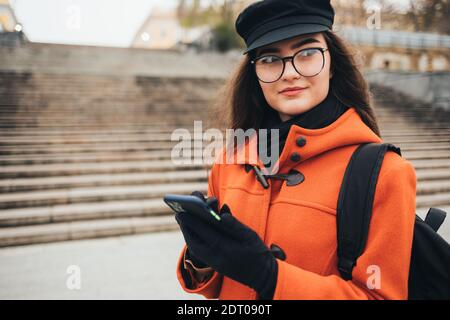 Frau in Mantel und Hut nutzt Handy im Freien in Herbst Stockfoto