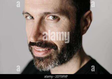 Nahaufnahme eines hübschen bärtigen Mannes mittleren Alters gegen Neutral Hintergrund Stockfoto