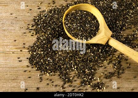 Chia Samen Salvia hispanica in Holzlöffel auf alten Holztisch Hintergrund. Gesunde Lebensmittel, Superfood Stockfoto