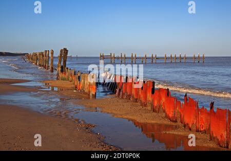 Ein Blick auf eine Vielzahl von verfallenen Wellenbrecher bleibt bei niedrigem Wasser an der North Norfolk Küste bei Cart Gap, Happisburgh, Norfolk, England, Großbritannien enthüllt. Stockfoto