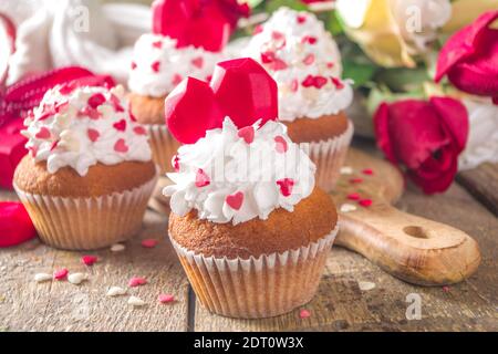Cupcake mit Herz für Valentinstag. Valentine Day Süßes Dessert, Vanille Cupcakes mit Schlagsahne Vanillecreme und roten Zuckerherzen Dekor für Valentinstag Stockfoto