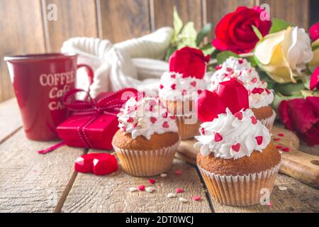 Cupcake mit Herz für Valentinstag. Valentine Day Süßes Dessert, Vanille Cupcakes mit Schlagsahne Vanillecreme und roten Zuckerherzen Dekor für Valentinstag Stockfoto