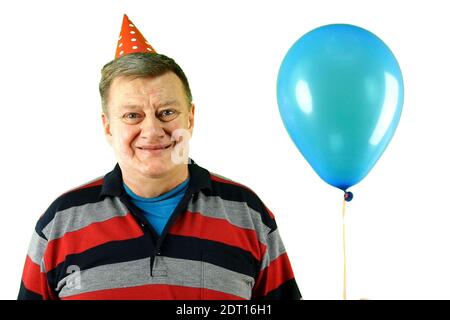 Reifer erwachsener Mann kaukasischer Ethnie in lässiger Kleidung und Geburtstagsmütze mit Luft Helium Ballon, lächelnd und frohlockend. Auf weißem Hintergrund ausschneiden Stockfoto