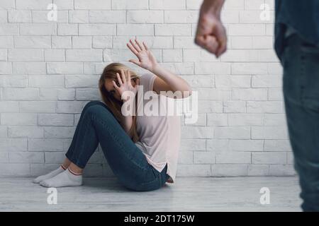 Schlagen und Selbstverteidigung zu Hause. Aggressiver Mann im Begriff, verängstigte Frau anzugreifen Stockfoto