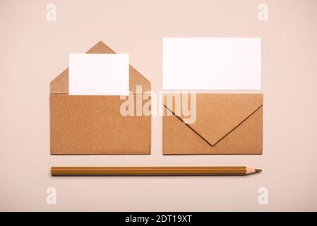 Braune Papierumschläge mit weißen Karten und braunem Bleistift Ein heller Hintergrund Stockfoto