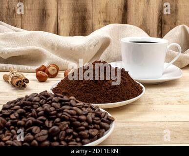 Drei Stufen der Zubereitung von gemahlenem Kaffee, Getreide, Getränk. Kaffeezutaten. Geröstete Kaffeesorten auf dem Hintergrund von Tassen mit Kaffee Stockfoto