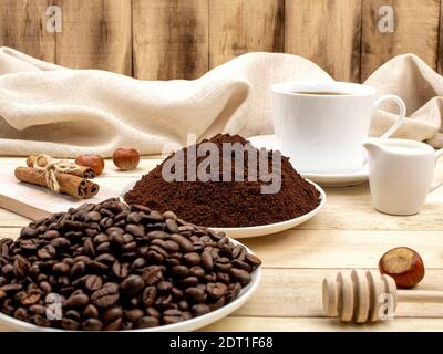 Drei Stufen der Zubereitung von gemahlenem Kaffee, Getreide, Getränk. Kaffeezutaten. Geröstete Kaffeesorten auf dem Hintergrund von Tassen mit Kaffee Stockfoto