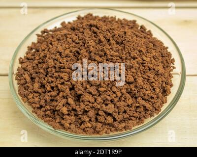 Granulierter Kaffee in einer Glasplatte auf einem Holzhintergrund Stockfoto