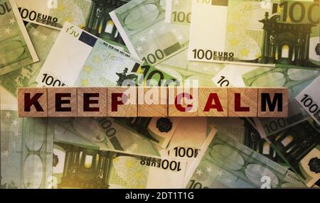 Halten Sie ruhige Worte auf Holzwürfel auf viele echte 100-Euro-Banknoten. Investitions- oder Darlehensgeschäft Konzept. Stockfoto