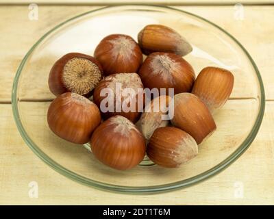 Haselnüsse in einer Glasplatte auf einem Holzhintergrund Stockfoto