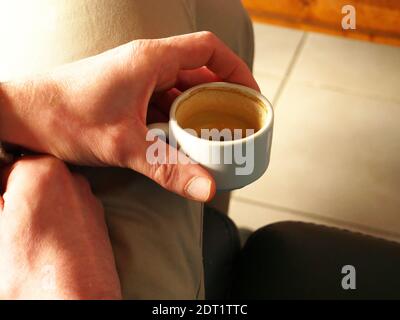 Nahaufnahme der Hand eines Mannes, der eine fast leere Tasse hält Kaffee Stockfoto