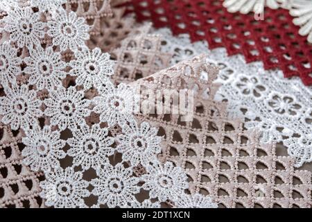 Stapel von rot, weiß. Beige gesetzt Segel Champagner sanften Luxus-Qualität guipure, Spitzenstoff auf grauem Hintergrund. Verwenden Sie für die Nähen Kleidung Leinendekoration. Stockfoto