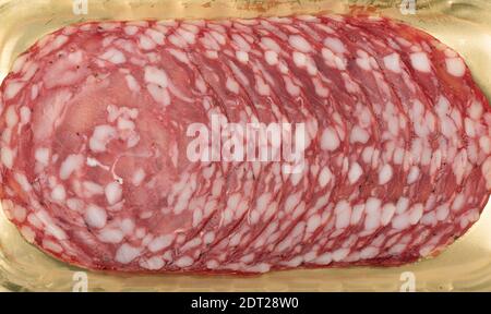 Dünne Scheiben Rohwurst auf goldenem Hintergrund. Hintergrund für das Essen. Stockfoto