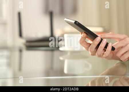 Nahaufnahme einer Frau Hand mit WiFi auf Smart Telefon mit Router im Hintergrund zu Hause Stockfoto