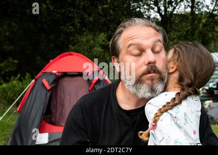 Mädchen umarmte ihren Vater auf dem Campingplatz Stockfoto