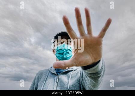 Mann mit Gesichtsmaske zum Schutz vor Virusinfektion. Jemandem sagen, er solle Abstand halten. Stockfoto