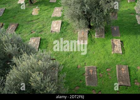 Jerusalem, Israel - 17. Dezember 2020: Grabsteine verstreut zwischen Olivenbäumen auf einem christlichen Friedhof in jerusalem. Stockfoto