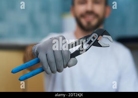 Erforderliches Handwerkzeug. Nahaufnahme der Hand eines jungen Reparaturers mit einem Rohrschlüssel Stockfoto