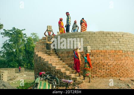 Bild eines Ziegelofens im abgelegenen Hooghly-Viertel. Erwachsene männliche und weibliche Arbeiter arbeiten hart, um die rohen Ziegel in den Ofen zu backen. Stockfoto