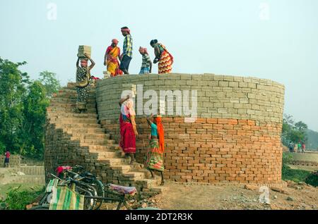 Bild eines Ziegelofens im abgelegenen Hooghly-Viertel. Erwachsene männliche und weibliche Arbeiter arbeiten hart, um die rohen Ziegel in den Ofen zu backen. Stockfoto